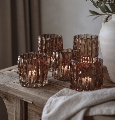 Bild av varma ljuslyktor på rustikt träbord med grön detalj