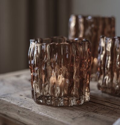 Bild på glaslykta i kastanjebrun färg på rustikt träbord