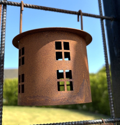 Bild av ljuslykta i metall som hänger på armeringsnät ute