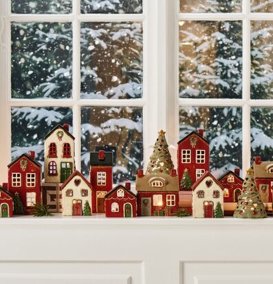 Bild av vintrigt fönster med keramikhus och jullyktor