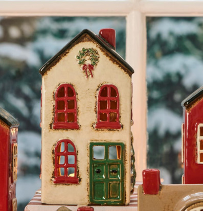 Bild på dekorativ ljuslykta som keramikjulhus i vintermiljö