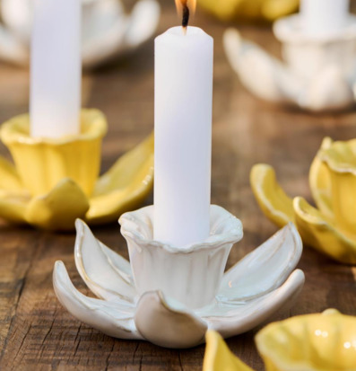 Bild av blomformade ljusstakar i creme och gult på träbord