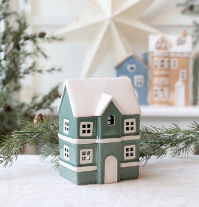 Bild av dekorativt husformad ljuslykta i vintrig miljö