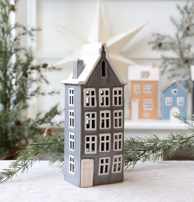 Bild på grå ljuslykta i form av hus med vinterdekor