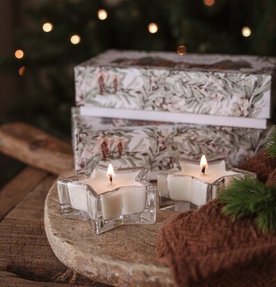 Bild av vinterstämning med doftljus, träfat och grankvistar