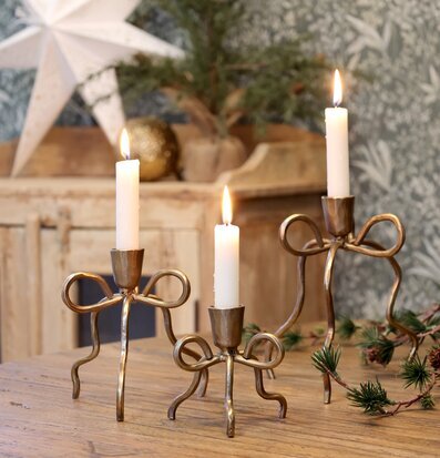 Bild med antika ljusstakar i mässing och rustik vintermiljö