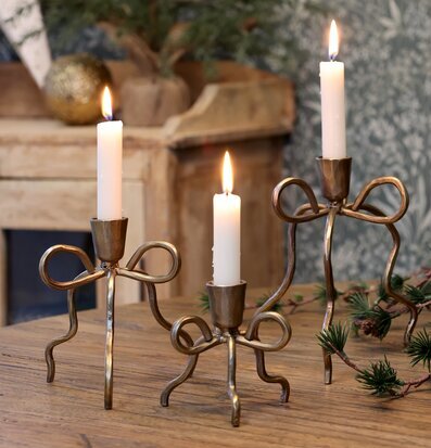 Bild av tre mässingsljusstakar på rustikt träbord vinterdekor