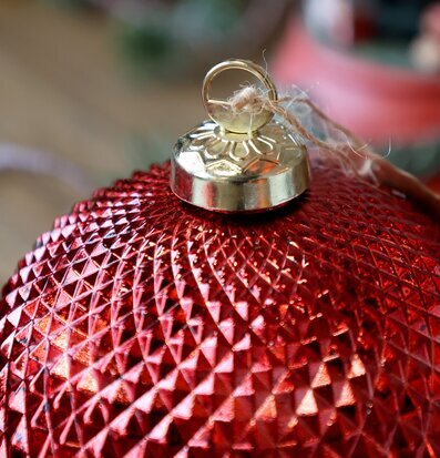 Bild på röd julkula med struktur och gyllene fäste