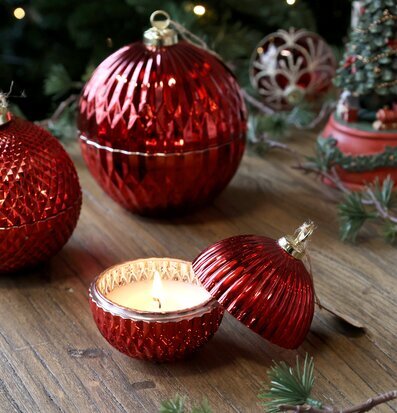 Bild på röda julkulor och ljuslykta i glas på träbord