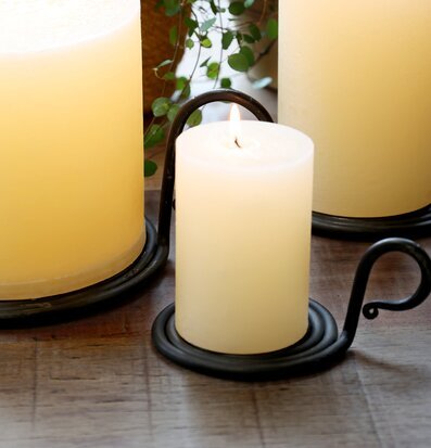 Bild på tända blockljus i kammarljusstake med grönska