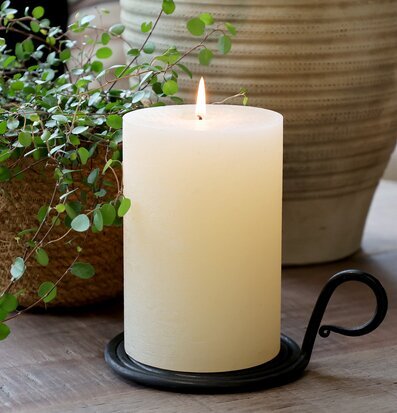 Bild av kammarljusstake med blockljus och grön växt på bord