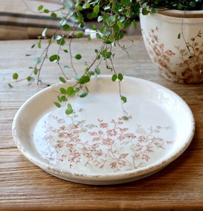 Bild av keramikfat med växtmotiv på rustikt träbord