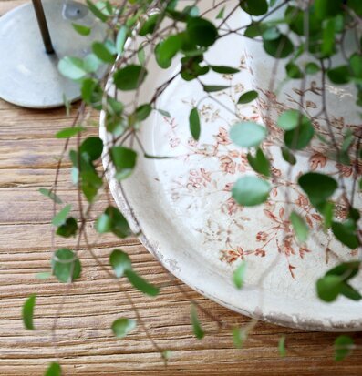 Bild av rustikt träbord med keramikfat, växt och ljusstake