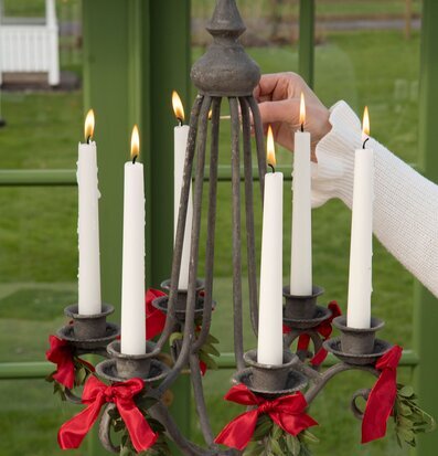 Bild på rustik ljuskrona med tända ljus och juldekorationer