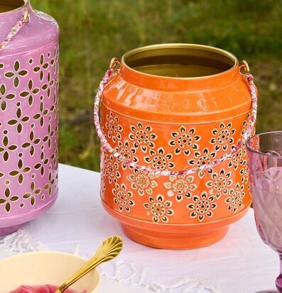 Foto: Orange metalllykta med blomutskärningar utebord