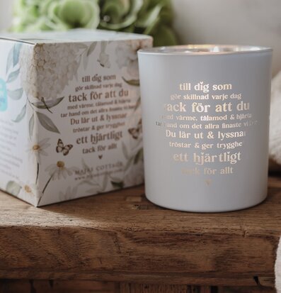 Foto: Ljuslykta med tänd låga och presentask på träbord