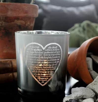 Bild av stilren ljuslykta med hjärtmotiv och text