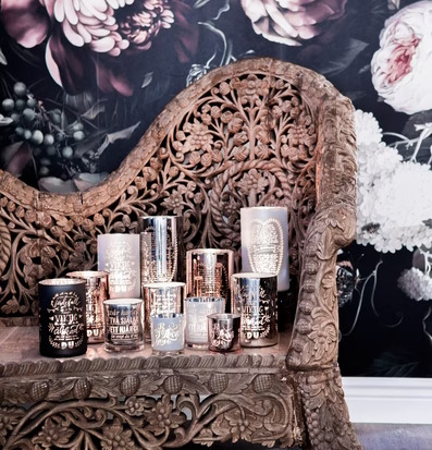 Bild av ljuslyktor på snidad träsoffa med blommor