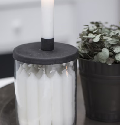 Bild av ljusstake i glasburk med stearinljus och växt