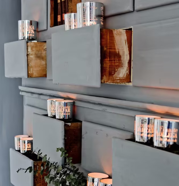 Bild av ljuslyktor på hyllor i rustik vägginstallation