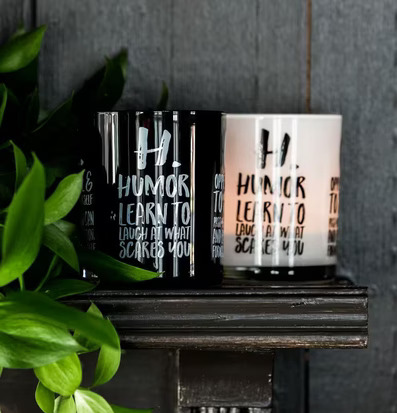 Bild av stilrena ljuslyktor på mörk träyta med växt