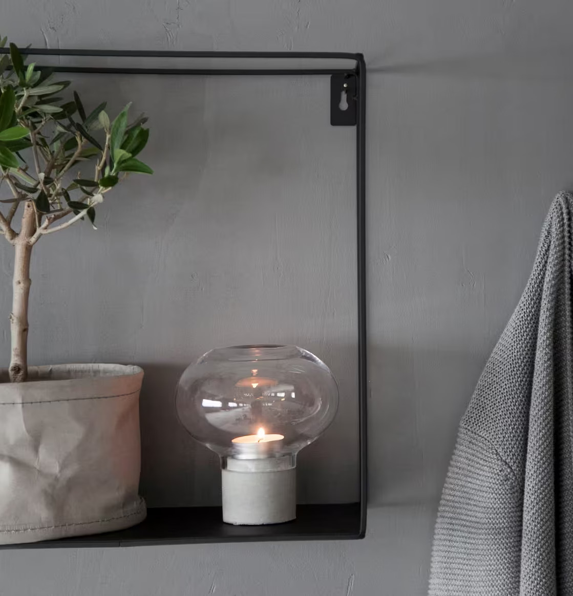 Bild av harmonisk inomhusmiljö med ljusstake och olivträd