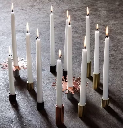 Foto av tända ljus på stengolv med stilrena ljusstakar